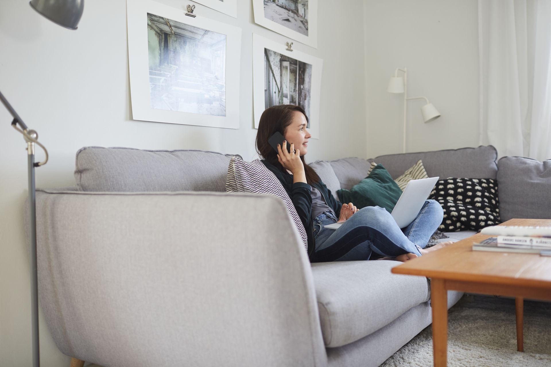 Kvinna som sitter och pratar i en telefon i en soffa Kvinna som sitter och pratar i en telefon i en soffa