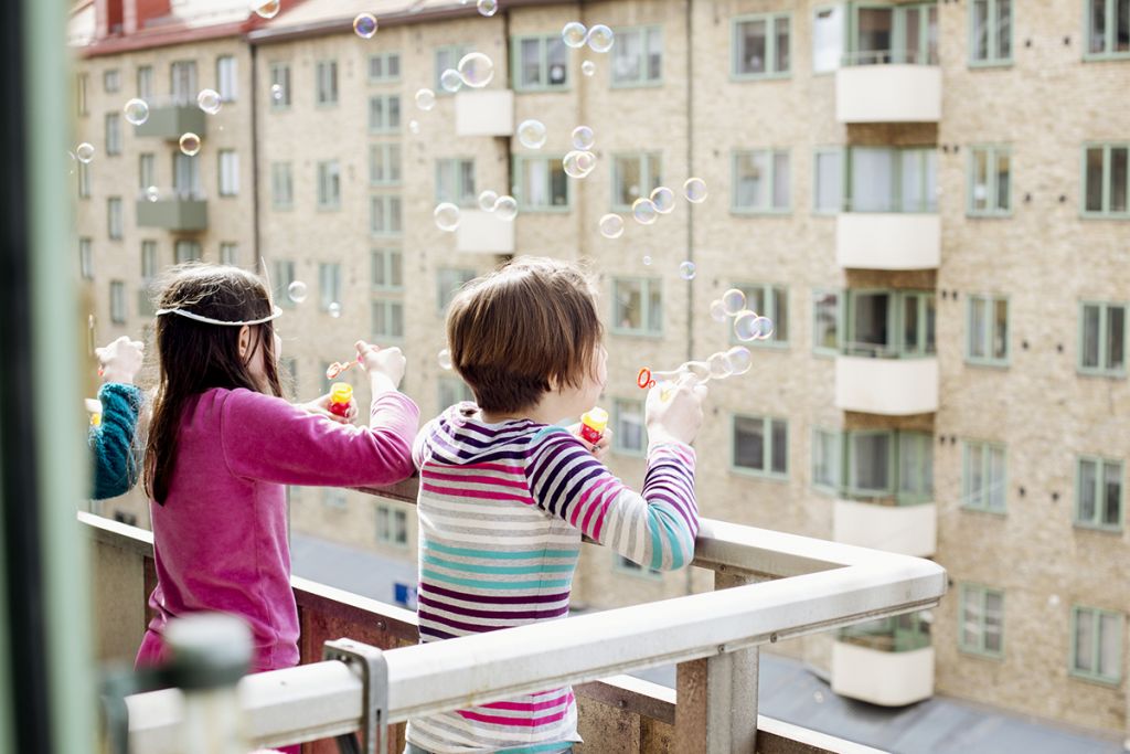 Barn blåser såpbubblor från en balkong